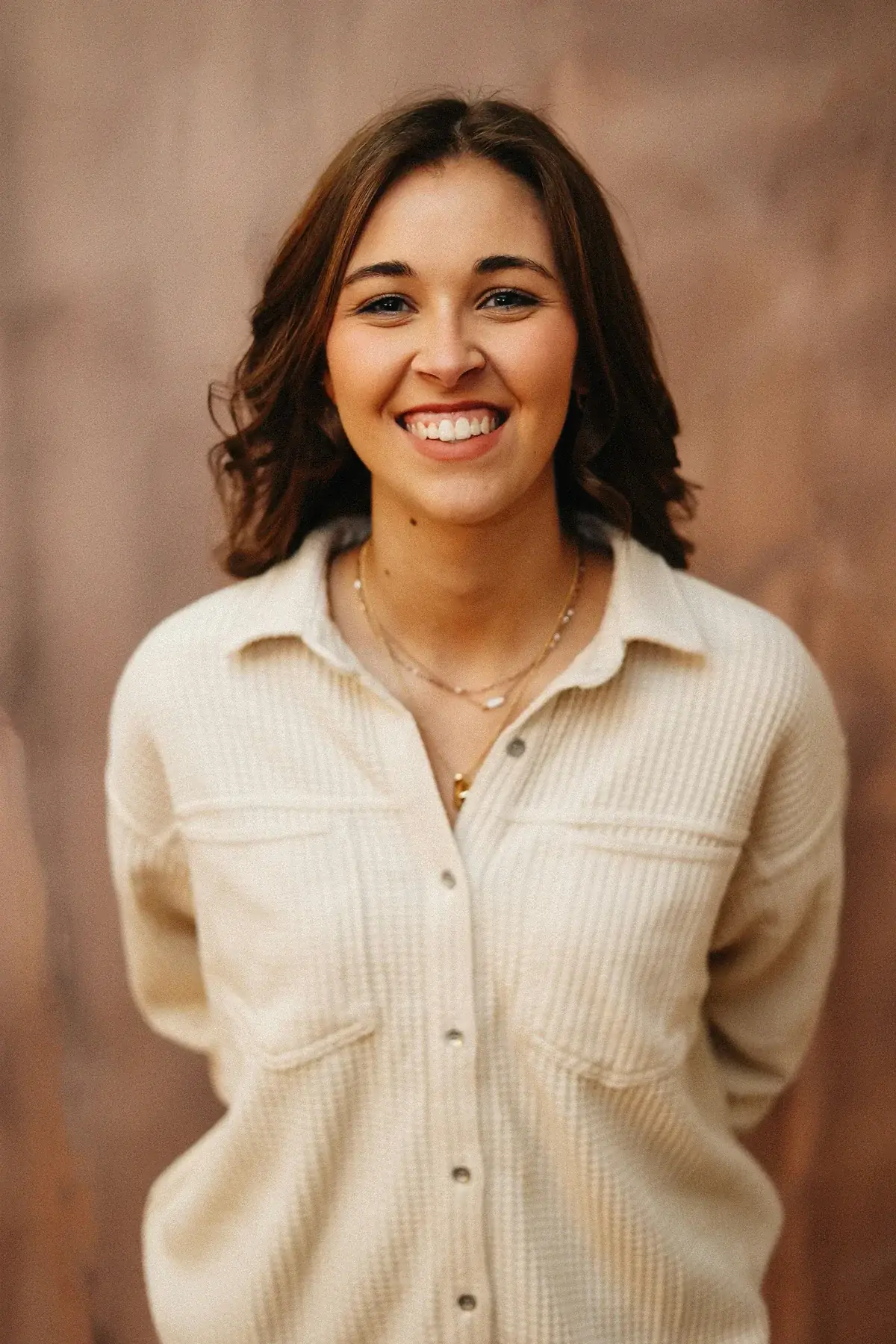 A smiling woman poses in front of a wall.
